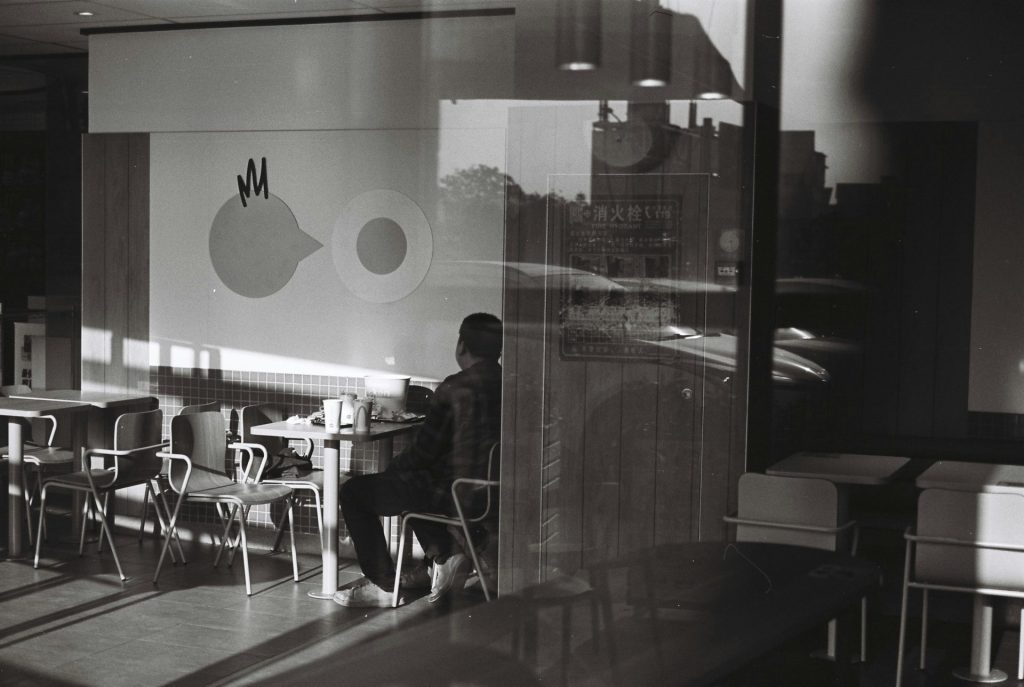 Frau in schwarzer Jacke steht nahe Glaswand